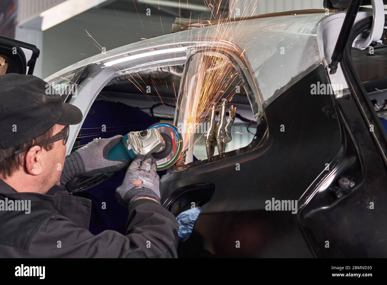 Repair service worker fix damaged car. Working with angle grinder to fix metal body. Stock Photo