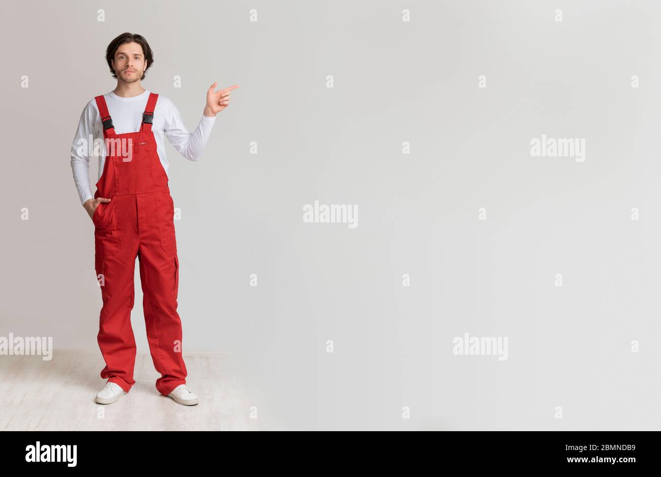 Confident young laborer in work uniform pointing aside at copy space Stock Photo