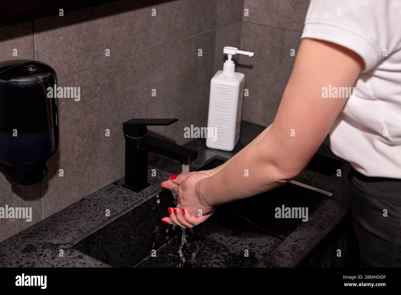 Woman washing hands for virus pandemic prevention, wetting hands with running water. Stock Photo