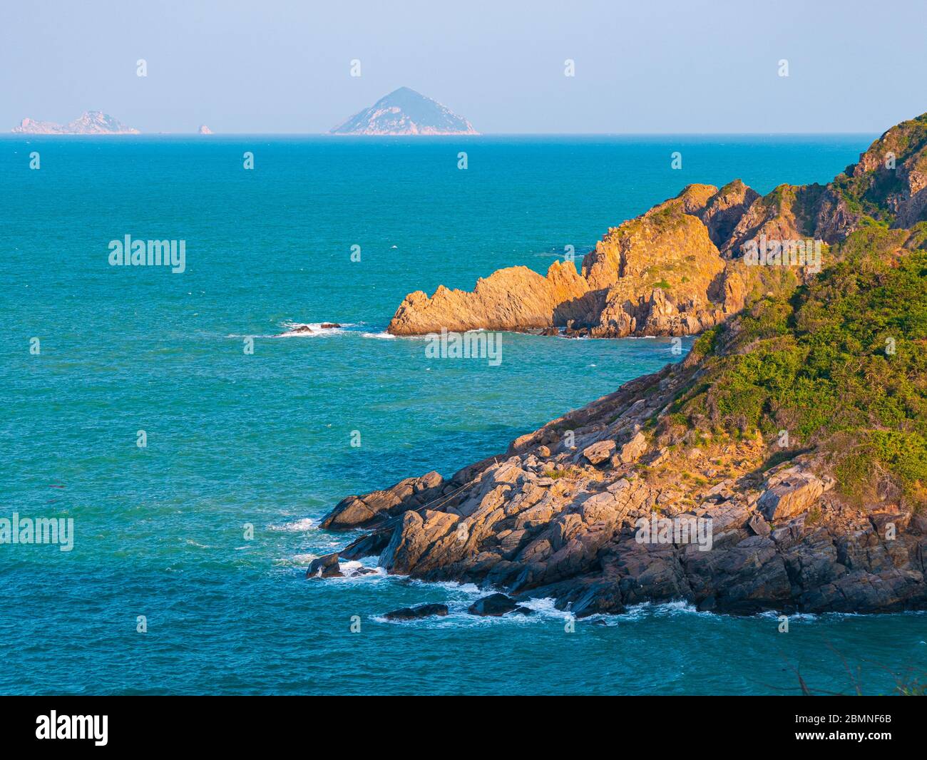 Expansive view of scenic tropical bay, lush green woodland and blue waving sea. The easternmost coast in Vietnam, Phu Yen province between Da Nang and Stock Photo