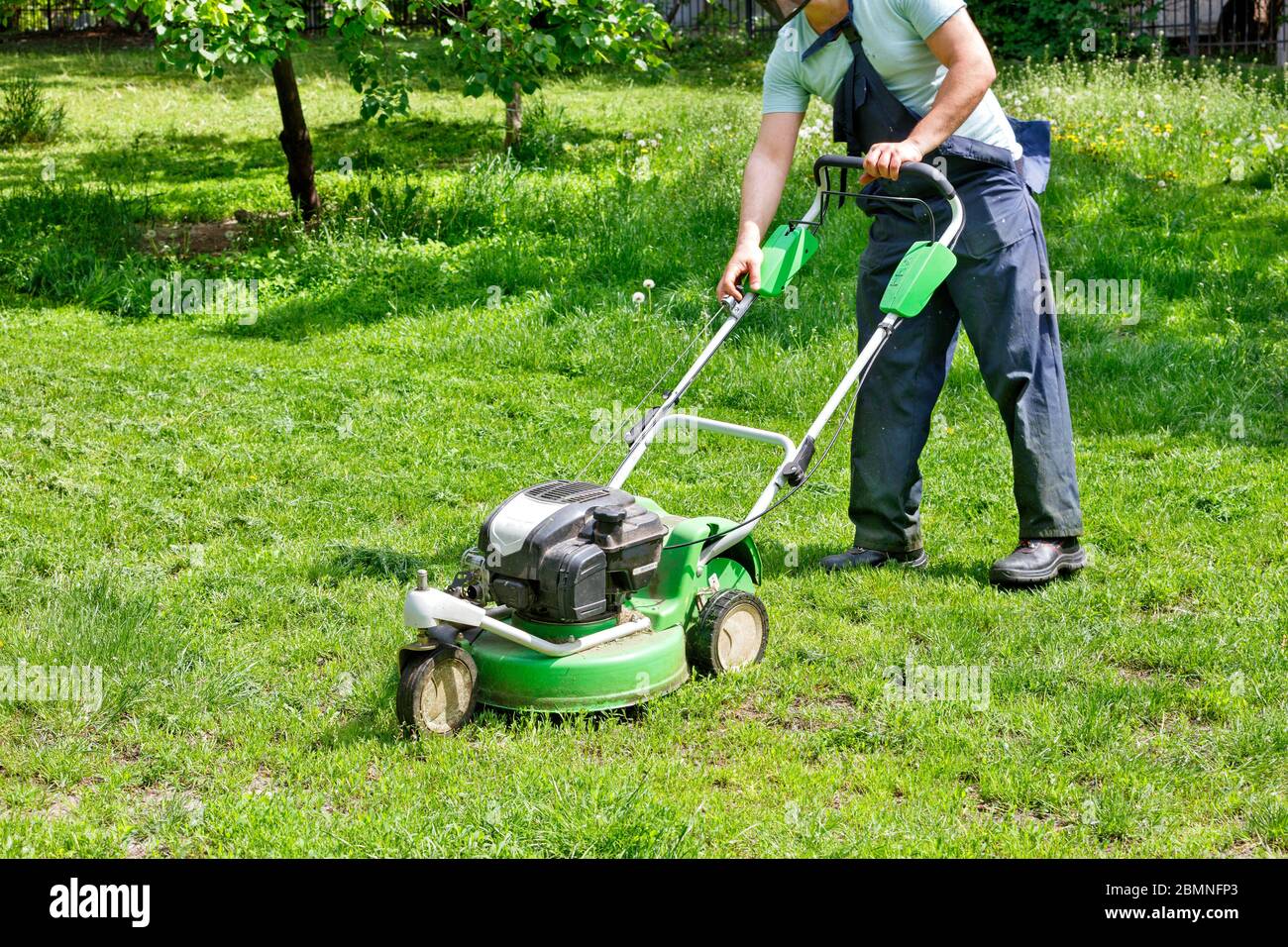 An industrial petrol, mower is ready to go and the gardener launches it to care for the green lawn in the city park, image with copy space. Stock Photo