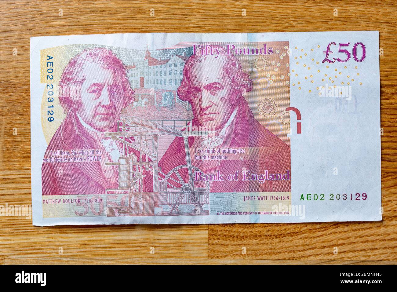 A Fifty pound note laying flat on an oak table, £50 cash banknote Stock ...