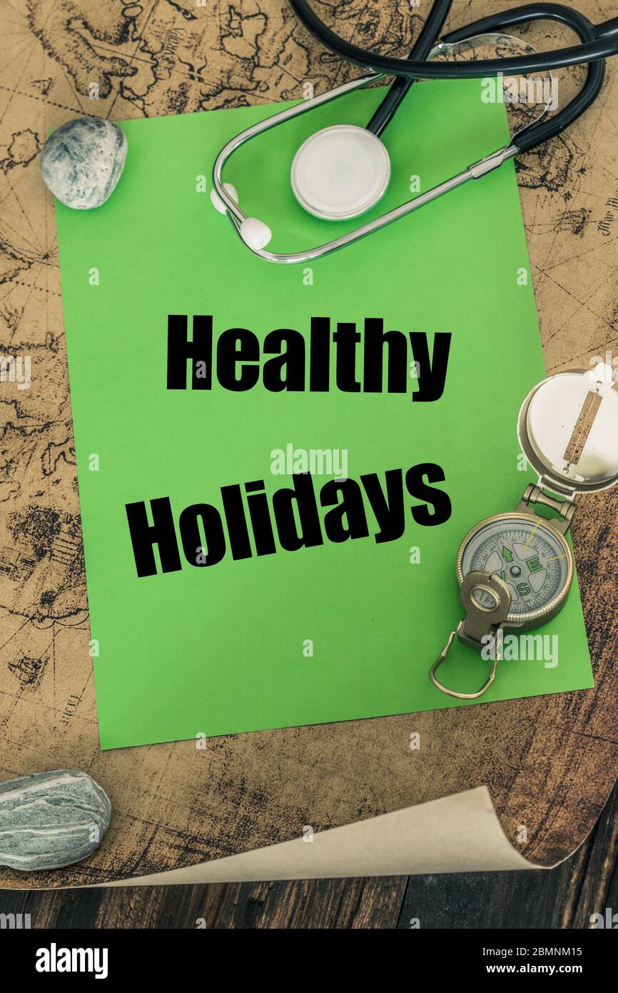 stethoscope, compass and a card with the words 'Healthy Holidays' on the background of an old map of the world, The concept of safe travel Stock Photo