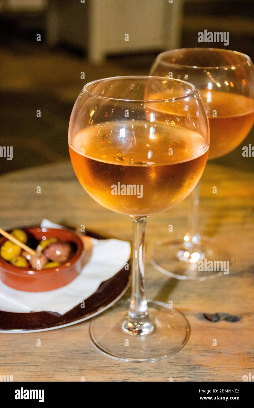 A glass of cold chilled rose wine served at a restaurant table. Water droplets are dripping from