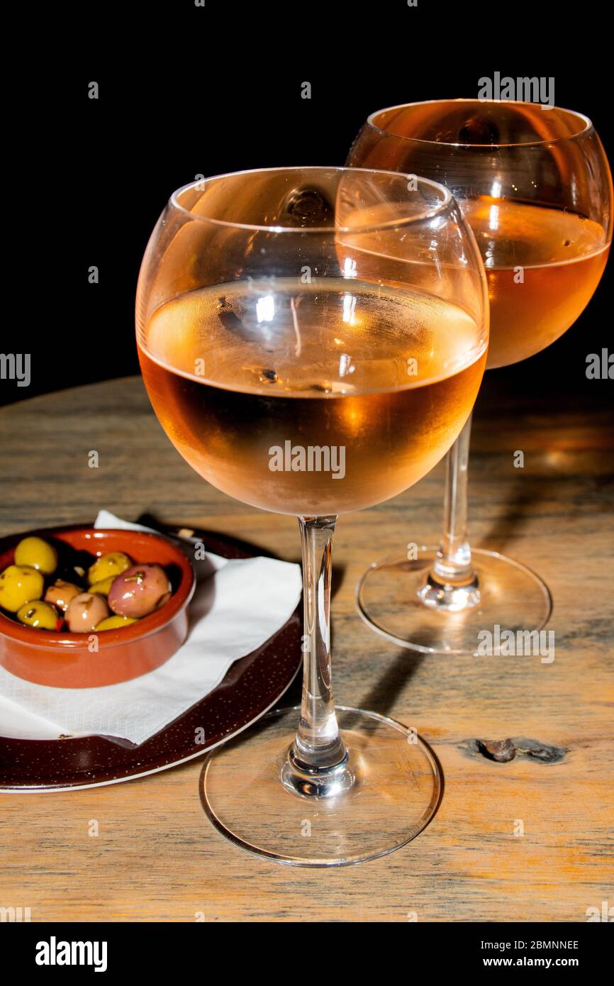 A glass of cold chilled rose wine served at a restaurant table. Water droplets are dripping from