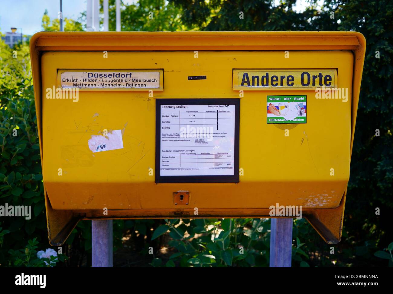Yellow public mail box (German: 'Briefkasten') made of steel plate. This one is for the Düsseldorf region. 'Andere Orte' means 'other destinations'. Stock Photo