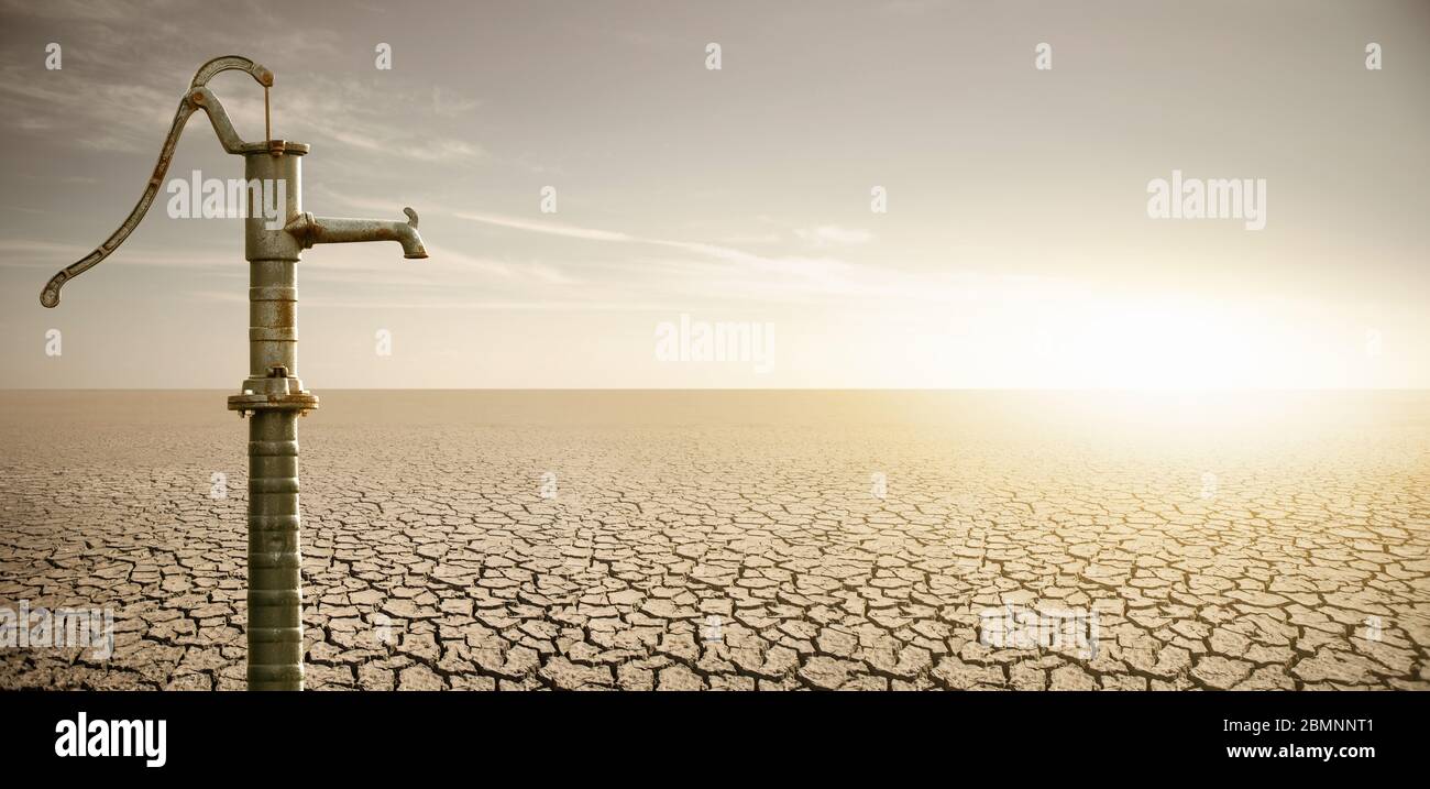 Dry cracked desert with rusty water pump. Drought and water scarcity caused by global warming Stock Photo