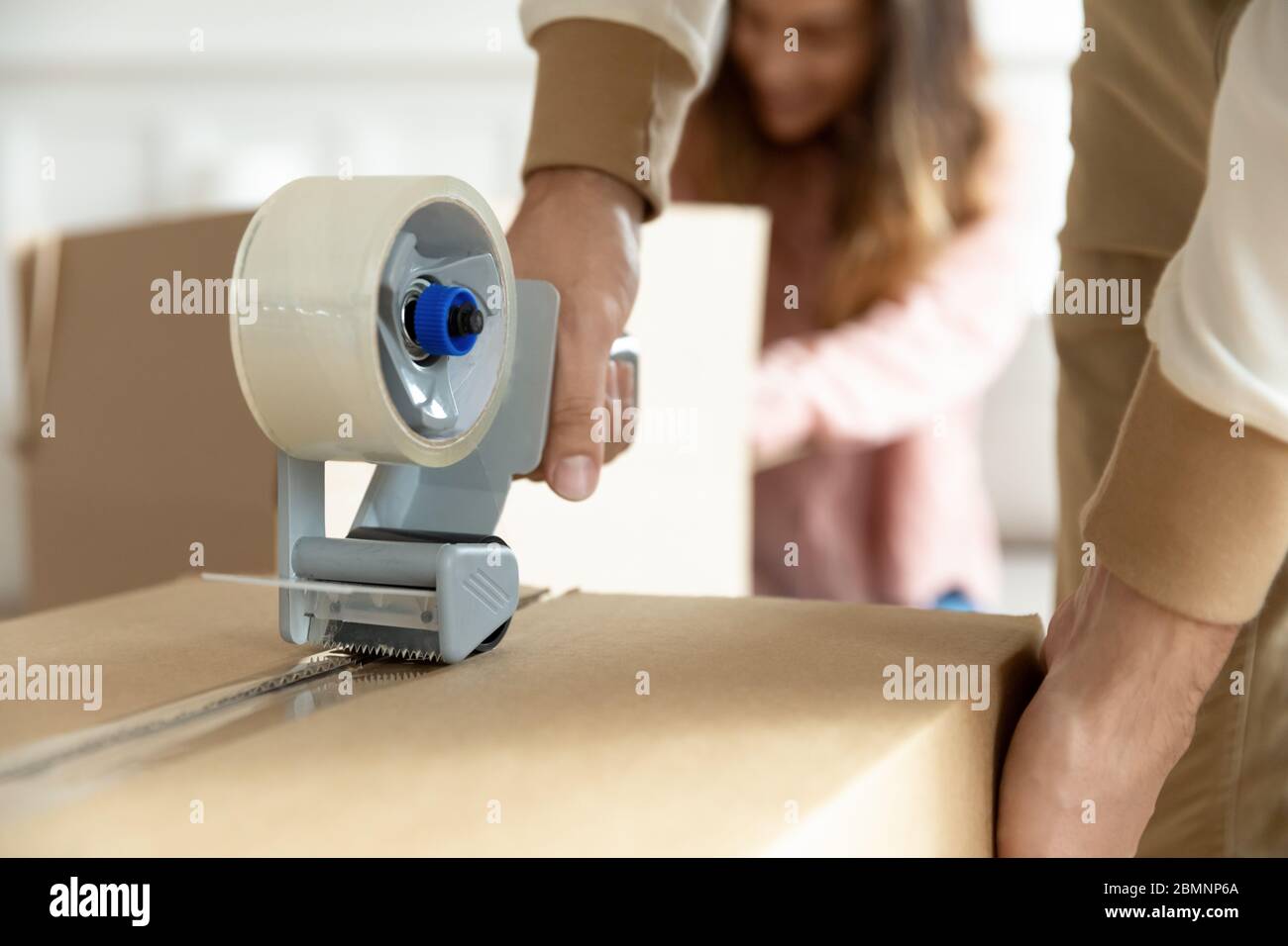 Close up family packing cardboard boxes with adhesive tape Stock Photo