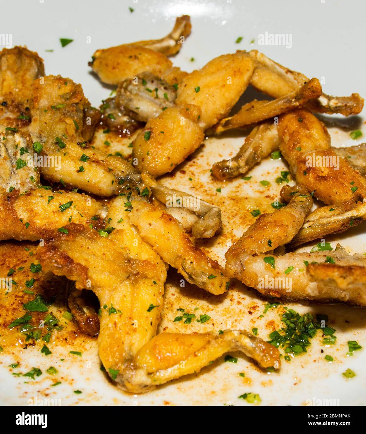 Grenouille: The French Delicacy of Frog Legs being served in a white plate at a traditional cuisine restaurant in Nice, France. Stock Photo