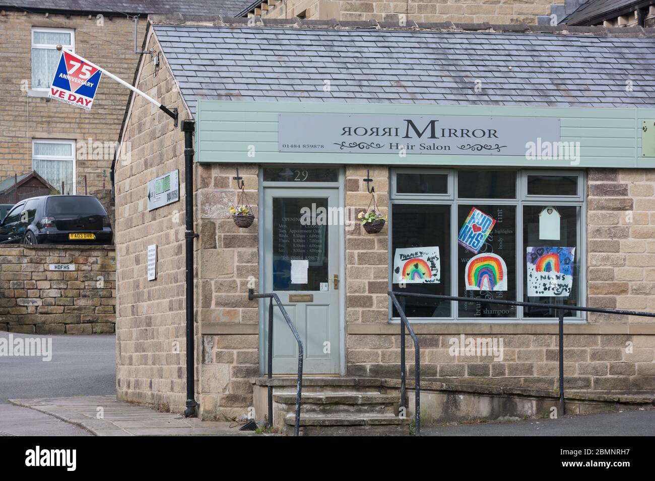 Meltham, UK - May 5 2020: A VE day flag and rainbow drawings displayed on a hair salon in Meltham, West Yorkshire. Stock Photo