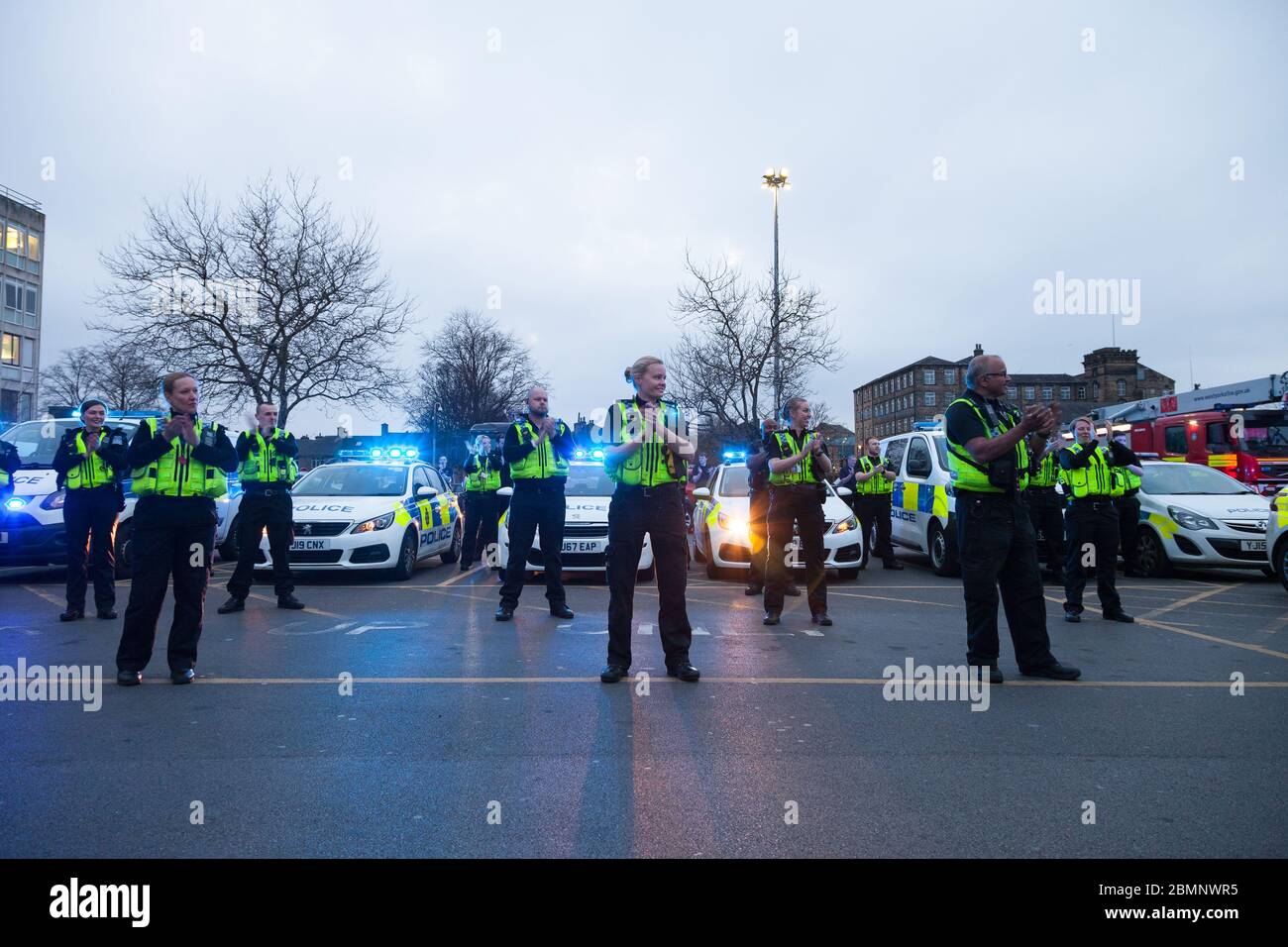 Police officers applaud NHS workers in front of Huddersfield Royal Infirmary in the weekly Clap for our Carers during the 2020 Coronavirus outbreak. Stock Photo