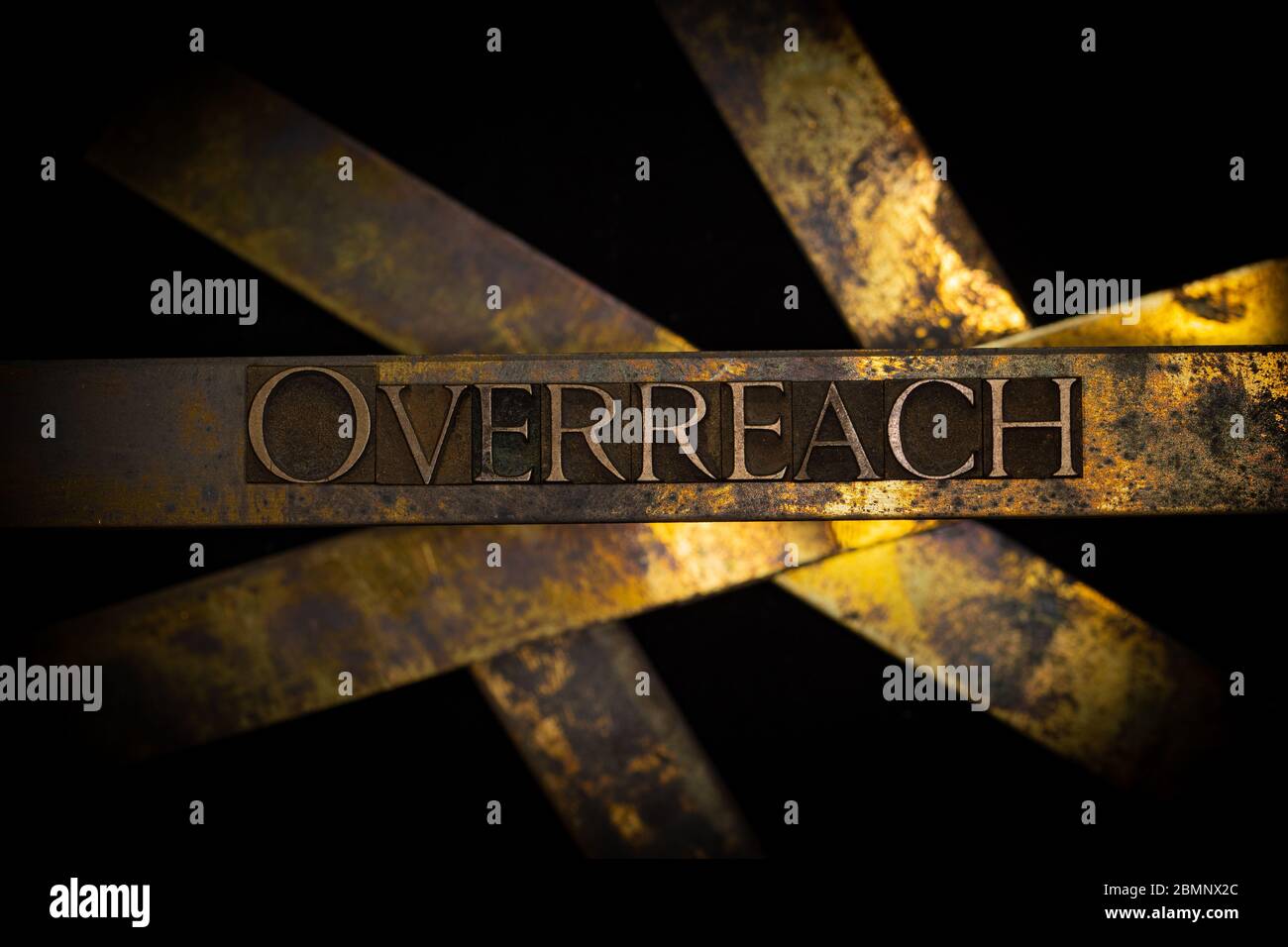 Photo of real authentic typeset letters forming Overreach text on vintage textured grunge copper and black background Stock Photo