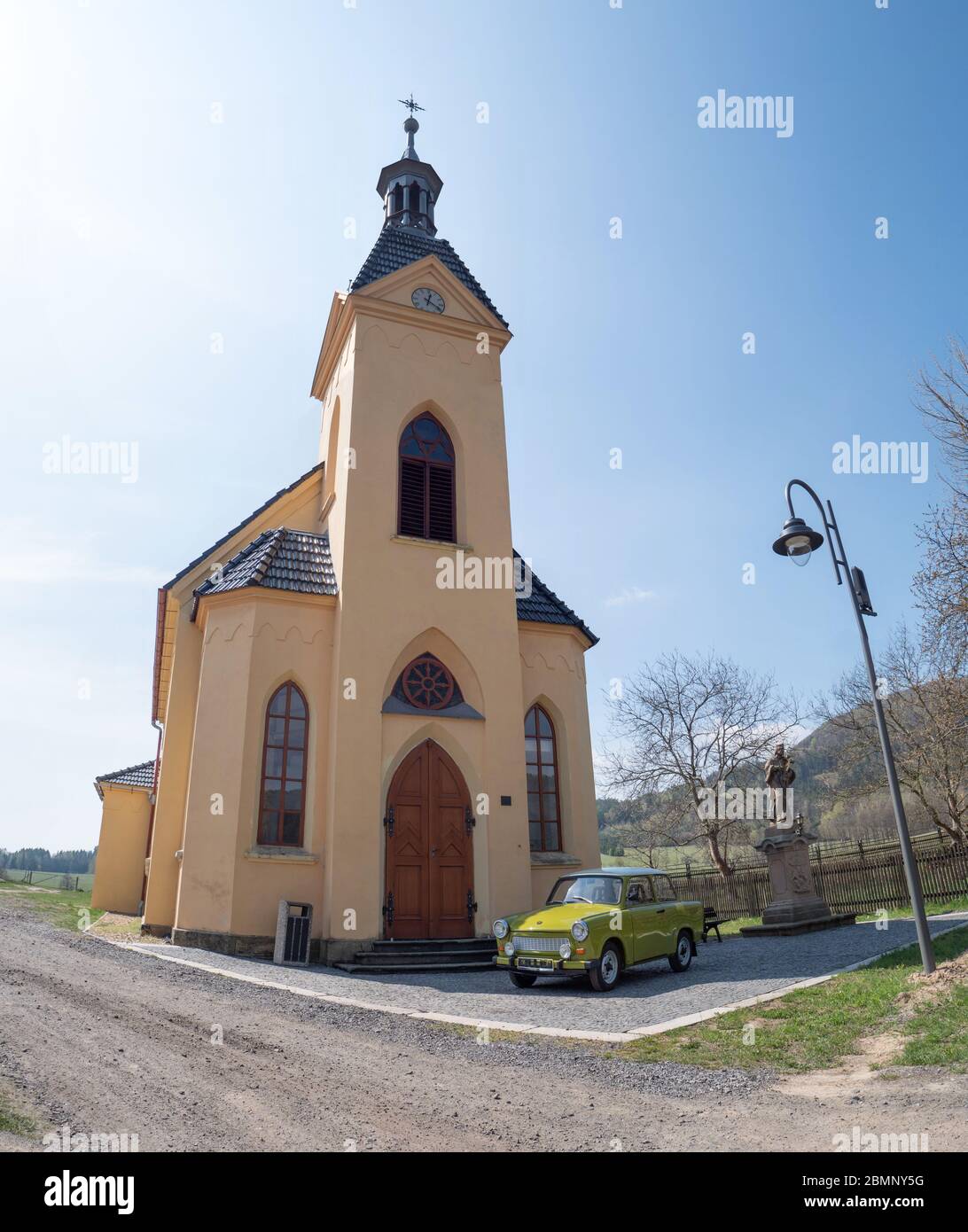 Green Trabant sedan car parking in front of entrance of church of St. Anthony.  17th of April 2020, Hermanice v Podjestedi, Czech Republic Stock Photo