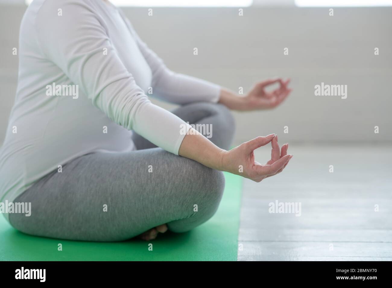 Close-up of female sitting in lotus pose, her hands in Gyan mudra Stock Photo