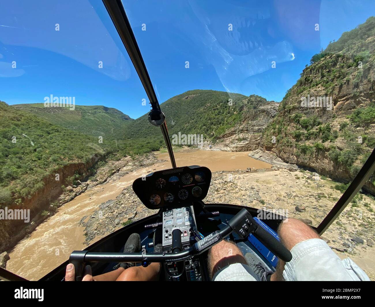 The helicopter pilot is on final approach to a small landing zone next to the waterfall. Here precision flying is required to land safely. Stock Photo