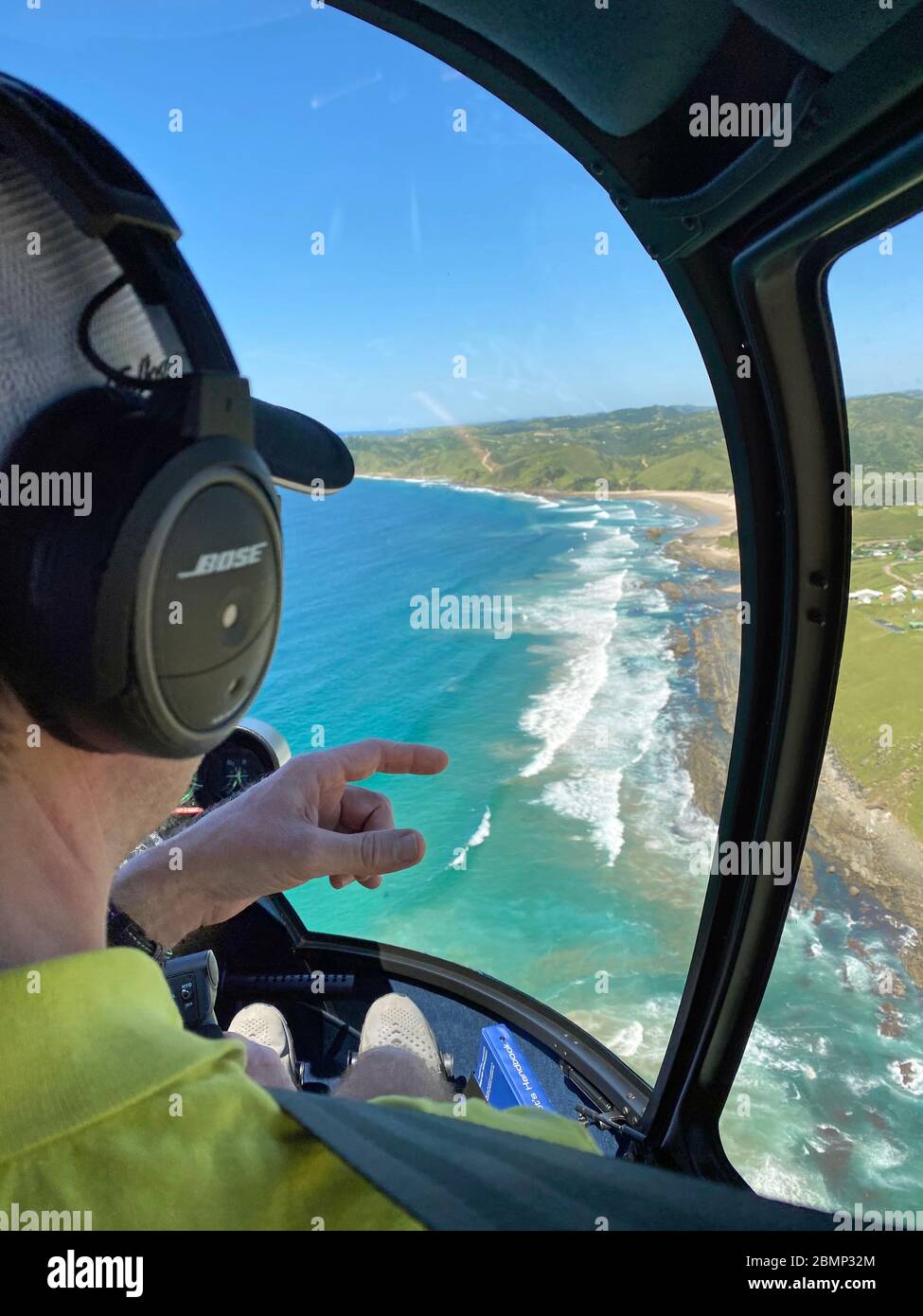 The helicopter pilot has spotted a group of dolphins near the coast. He is indicating to his passengers where the wild animals are in the water. Stock Photo