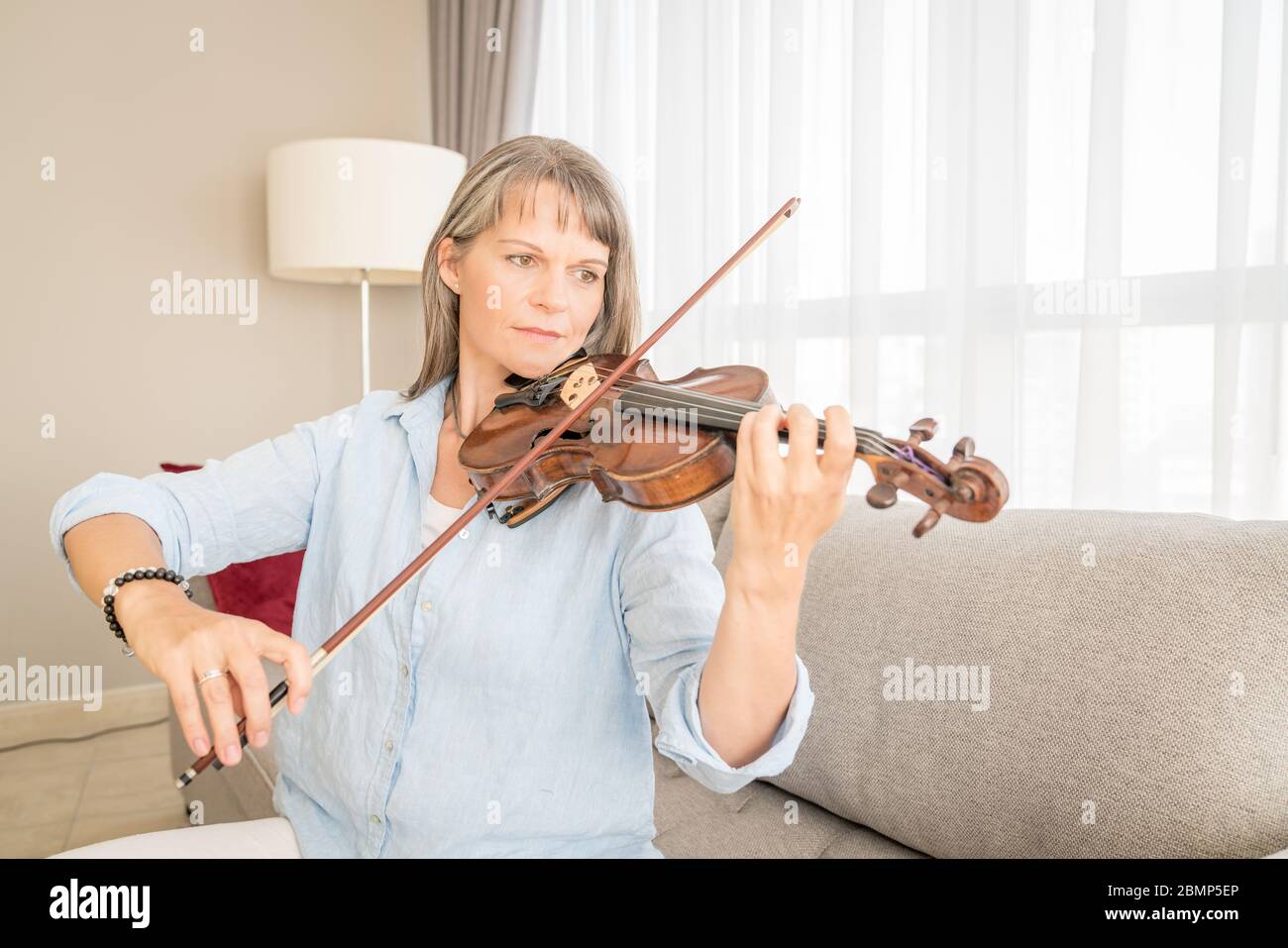 Mature woman playing violin in her urban apartment Stock Photo Alamy