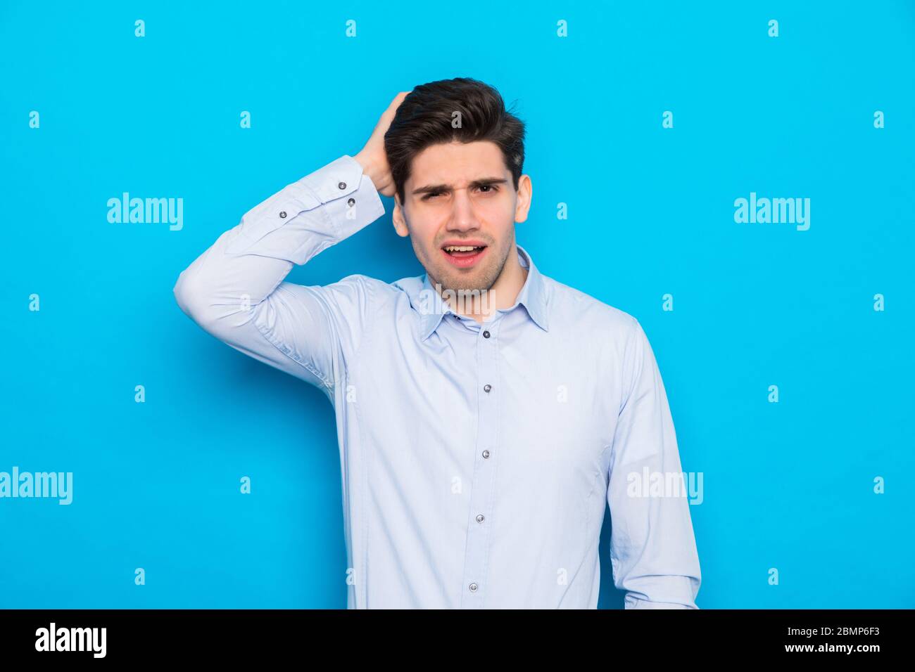 Young handsome man wearing casual shirt standing over isolated blue background confuse and wonder about question. Stock Photo