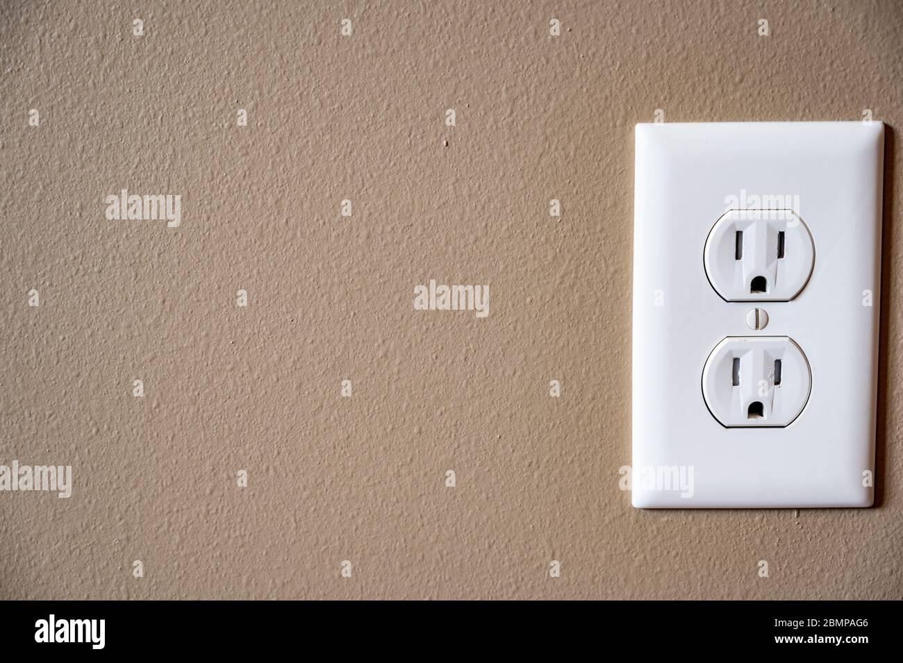 white dual electrical outlet with plate cover on beige colored drywall