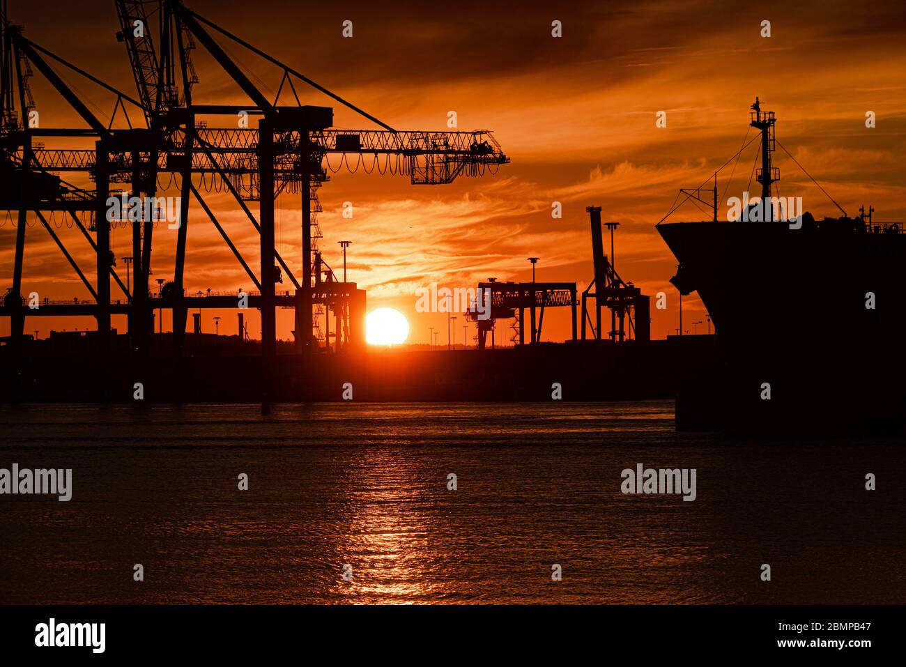 Profile of a large ship and container cranes at sunset Stock Photo - Alamy