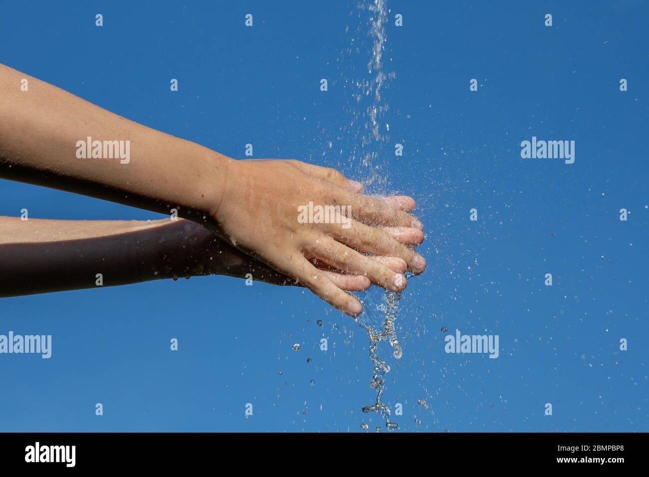 Young people rub and wash their hands under water jet Stock Photo