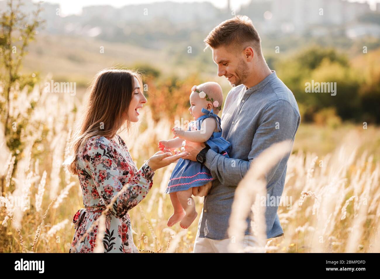 mom, dad and little girl having fun outdoors in the grass on summer day ...
