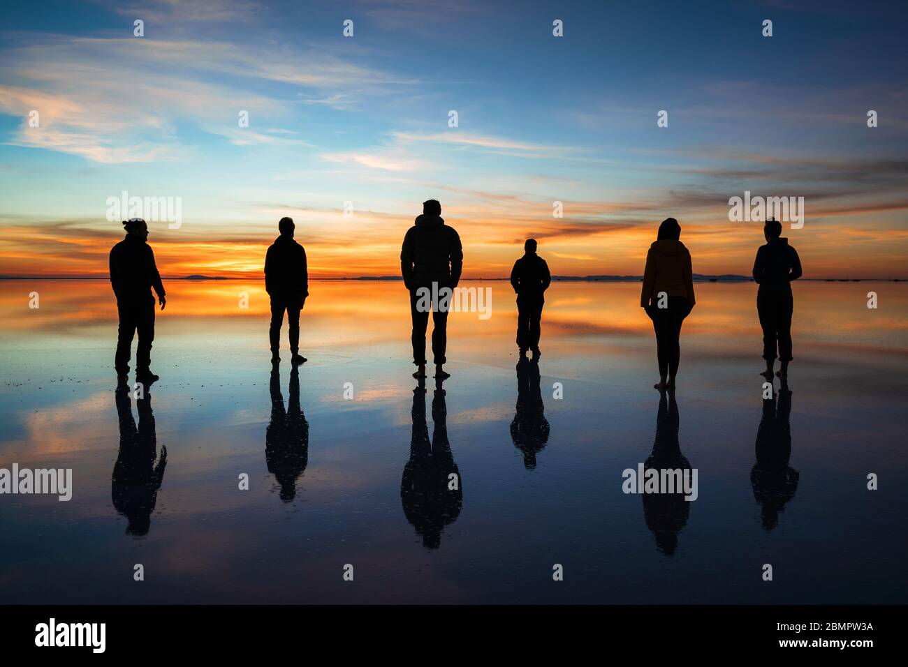 Group of travellers silhouette against sunrise at Uyuni Salt Flats (Spanish: Salar de Uyuni ) in Bolivia, teamwork and leadership concept. Stock Photo