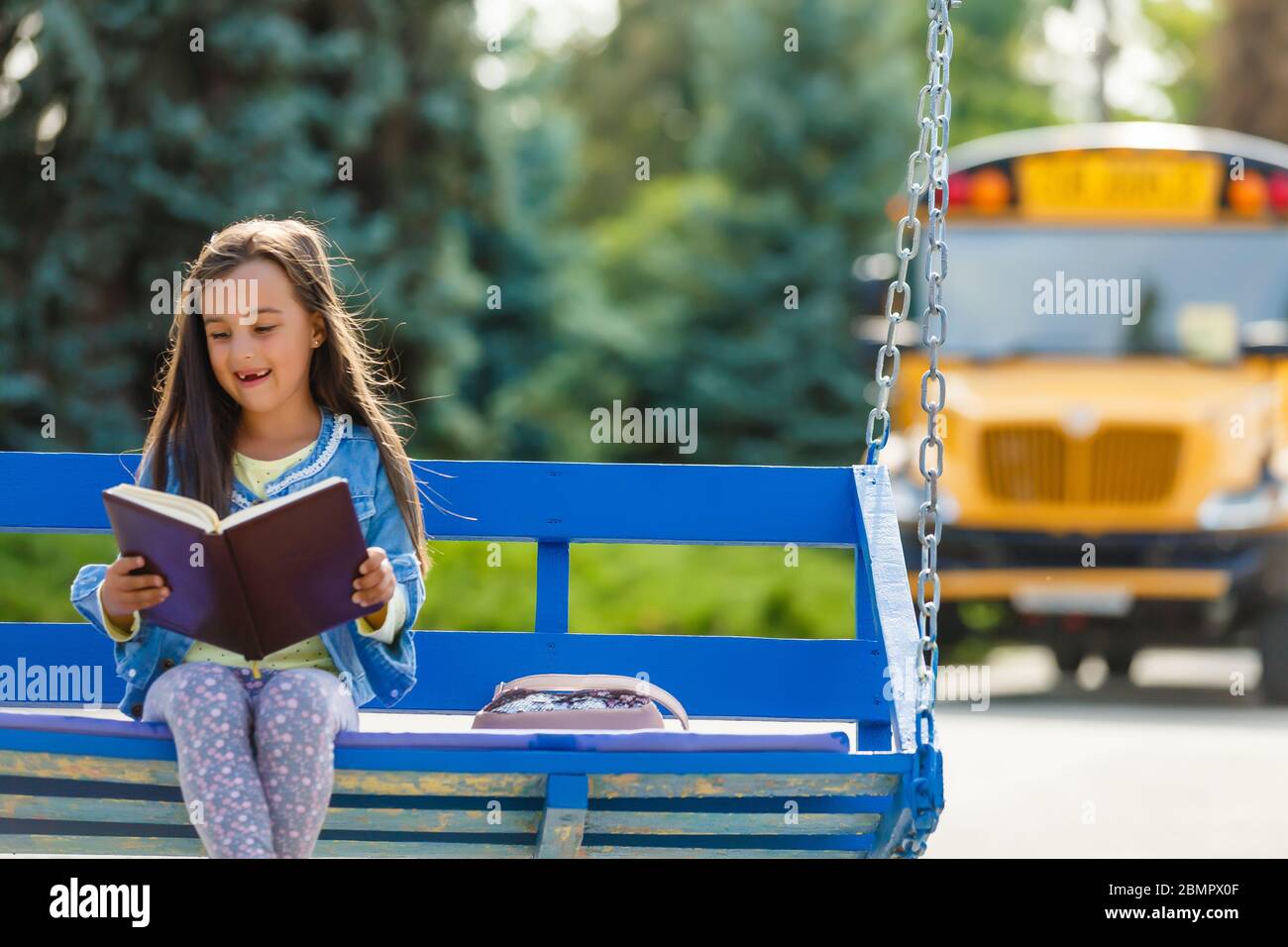 Little girl by a big school bus door with her pink backpack Stock Photo