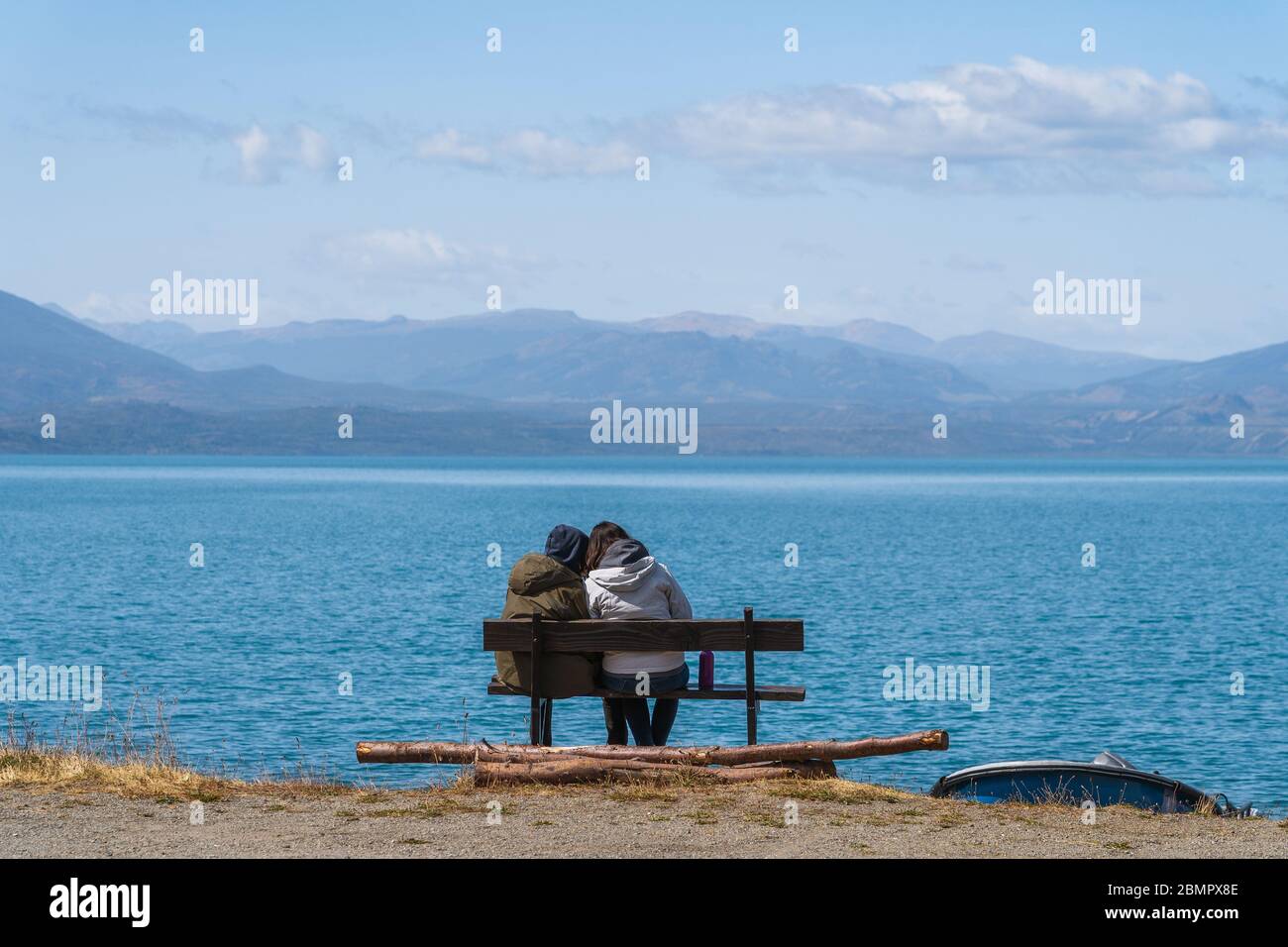 Couple sitting on bench by General Carrera Lake near Puerto Rio Tranquilo in Chile, Patagonia, South America. Stock Photo