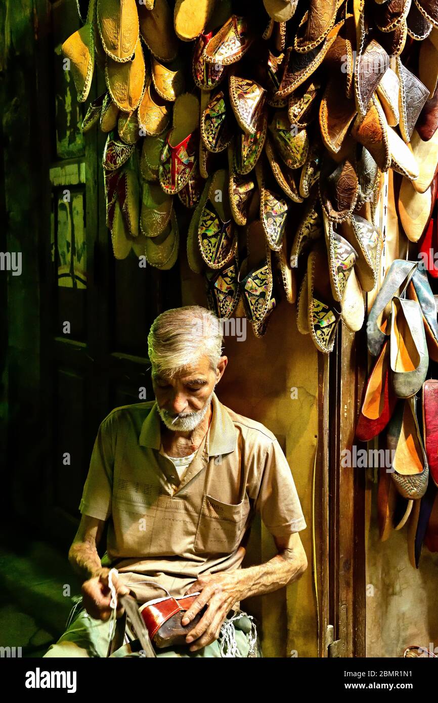 Shoe maker making camel hide leather slippers in the Tentmakers row section of Khan el-Khalili market in Cairo Stock Photo