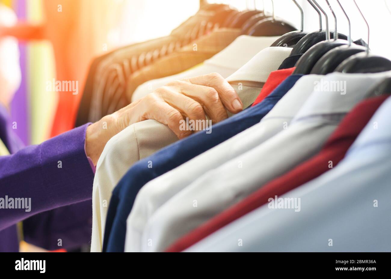 Men fashion clothes / Hanging clothes suit colorful or closet rack different coloured man suits in a closet on hangers in a store or showroom Stock Photo