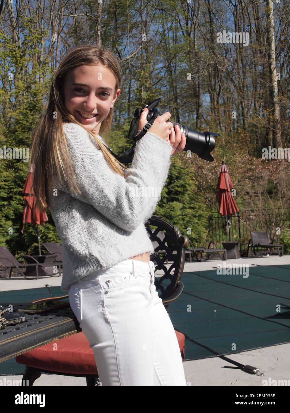 Young girl sharpening her new found skill with a DSLR camera on Mothers Day 2020 in Sparta, New Jersey. Happy with her results gets a big smile. Stock Photo