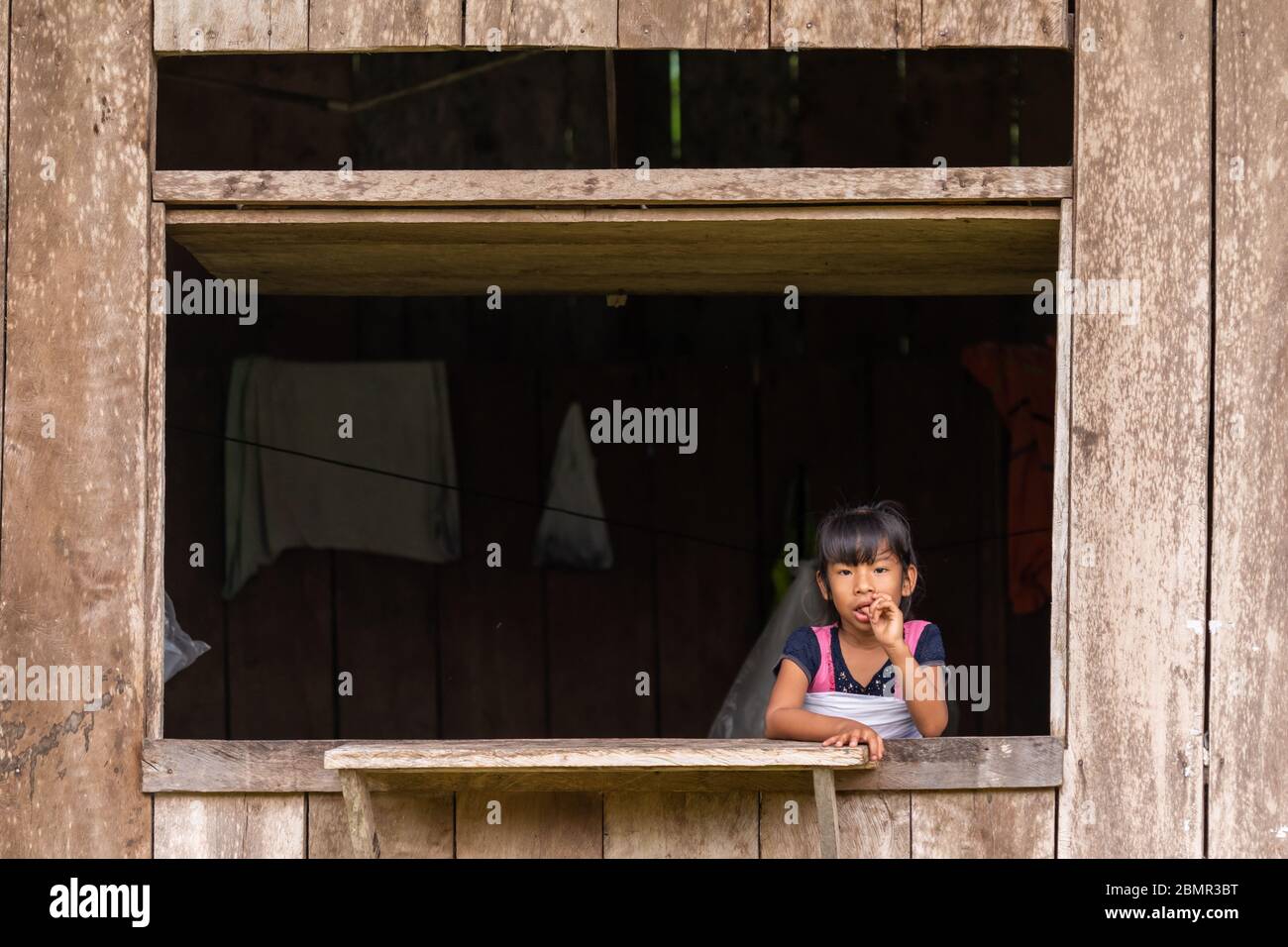 Riberenos child watches from a window in Peruvian Amazon Stock Photo
