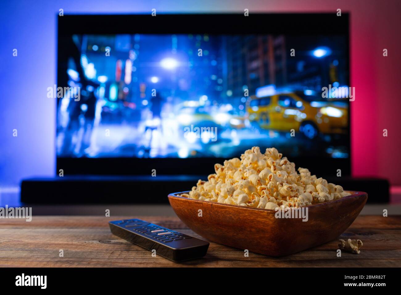 A wooden bowl of popcorn and remote control in the background the TV works.  Evening cozy watching a movie or TV series at home Stock Photo - Alamy