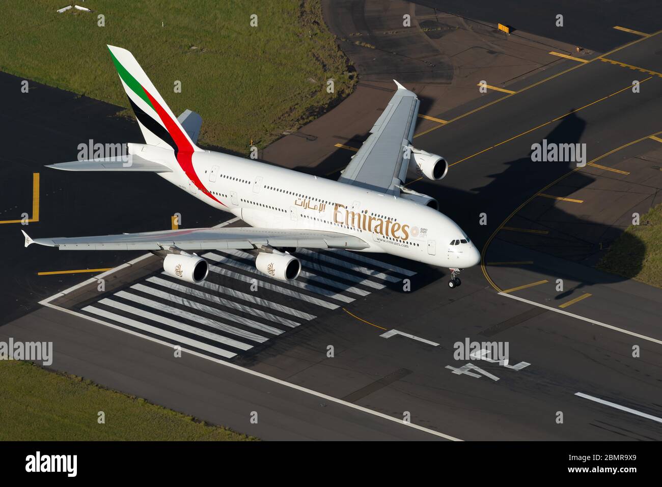 Emirates Airlines Airbus A380 aircraft over Sydney International Airport runway threshold before landing. Aerial view of huge A380 airplane. Stock Photo