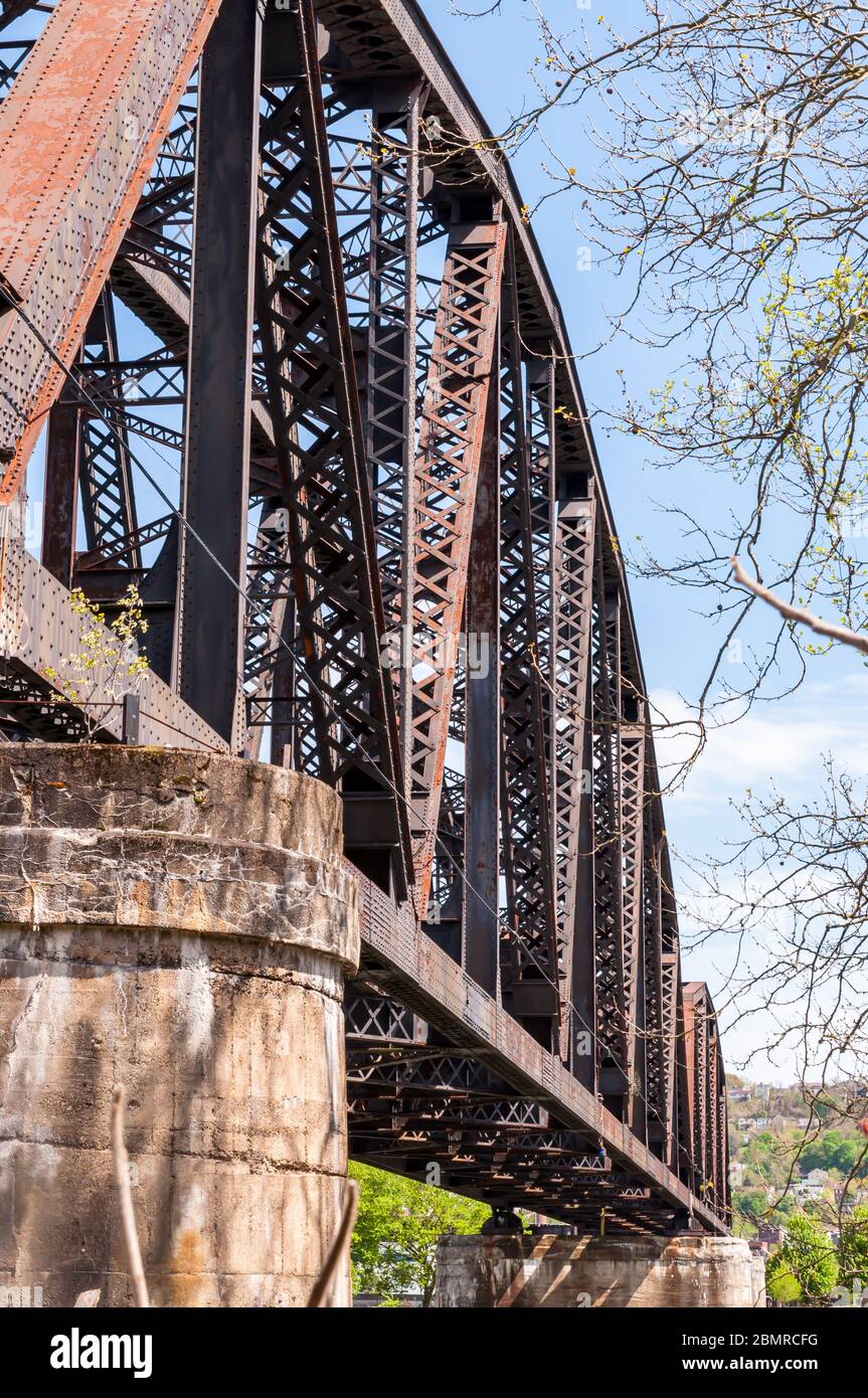 A steel railroad trestle bridge with concrete abutments on a sunny