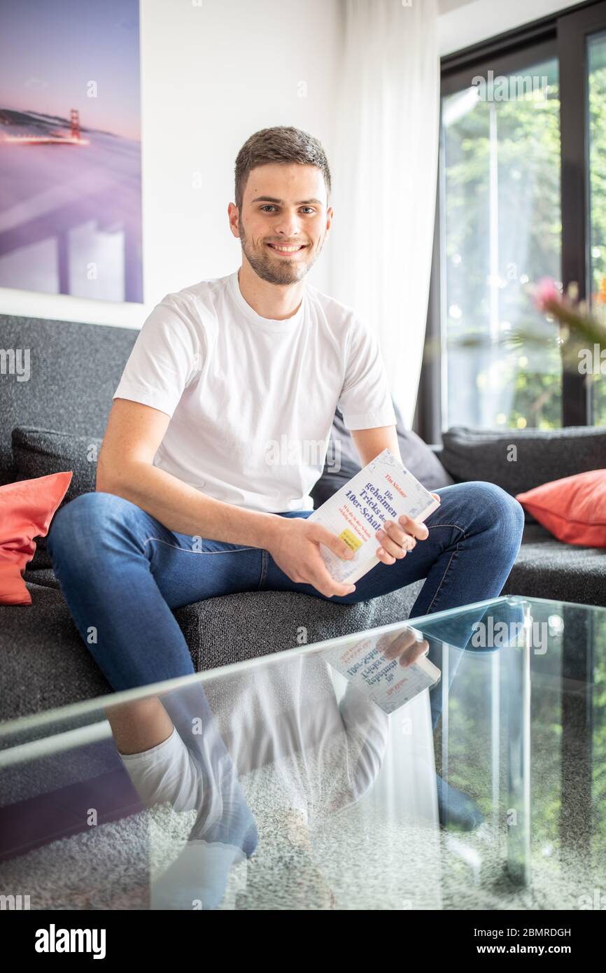 Haan, Germany. 09th May, 2020. Tim Nießner sits on a couch with his book 'The secret tricks of the 1.0 pupils'. The 18-year-old from Haan near Düsseldorf has come up with something special to prepare for his Abitur: He has interviewed almost 100 of the best high school graduates in Germany to find out what he can learn from them. This has resulted in a 300-page book entitled: 'Die geheimen Tricks der 1,0er-Schüler' (The Secret Tricks of the 1.0 Students), which will be published by mvg Verlag on 12.05.2020. Credit: Marcel Kusch/dpa/Alamy Live News Stock Photo