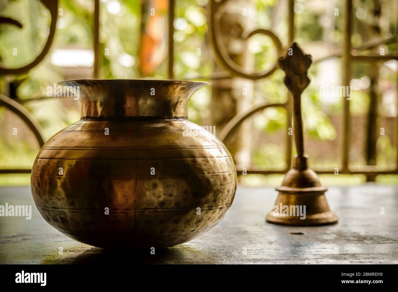 Close up Still Life of antique Holi water pot and bell on rustic floor. Faith, Tradition, Spirituality, Prayer, symbols of peace and Religious Themes. Stock Photo