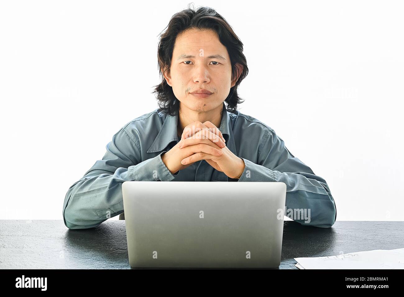 Asian businessman using laptop table sitting on desk table look at camera on white office background with copy space Stock Photo