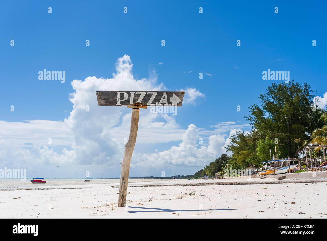 Pointer pizza on a wooden post on the tropical sand beach of Zanzibar island, Tanzania, East Africa. Travel and vacation concept Stock Photo
