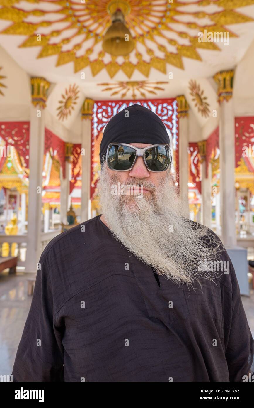 Face of mature bearded tourist man with sunglasses at the Buddhist temple Stock Photo