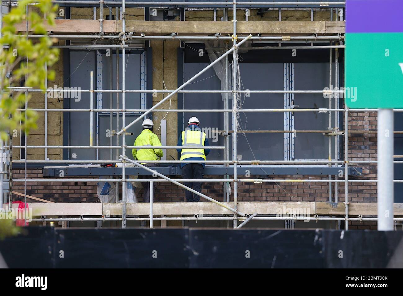Ashford, Kent, UK. 11 May, 2020. Coronavirus update, following the announcement by the government that workers who cannot work from home can go back to work construction workers on a large building site in the city centre are busy at work. Two builders are seen busy at work high up on scaffolding. ©Paul Lawrenson 2020, Photo Credit: Paul Lawrenson/Alamy Live News Stock Photo
