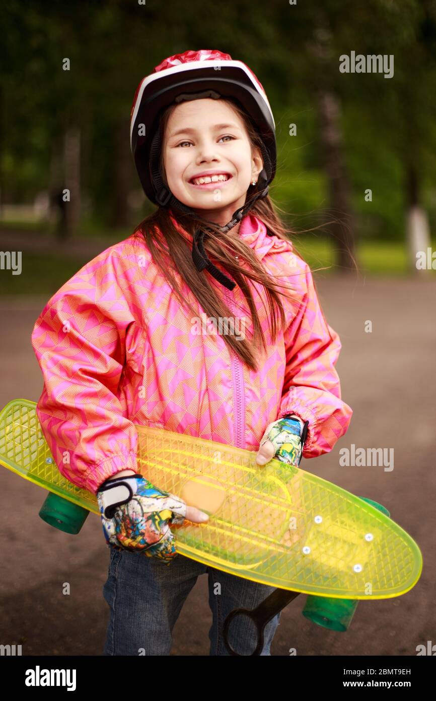Cute little preteen girl wearing helmet riding on a skateboard in