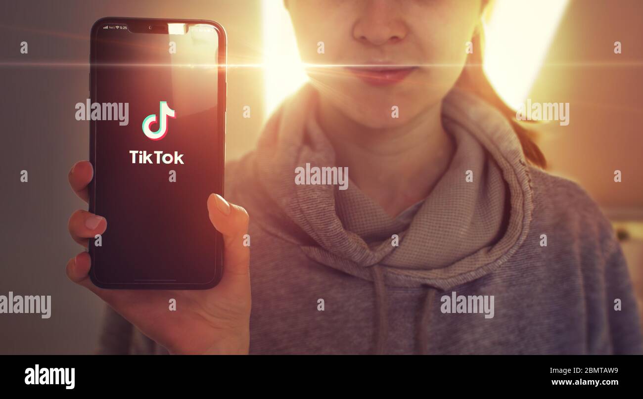 KYIV, UKRAINE-JANUARY, 2020: Tiktok on Smart Phone Screen. Young Girl Showing Mobile Phone Screen with Tiktok on it while Looking at the Camera. Focus on Smartphone. Stock Photo