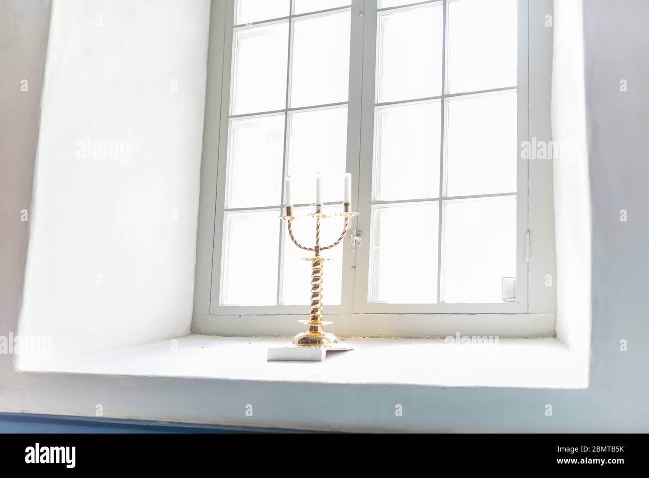 Candlestick for three candles in a chirch window.. Stock Photo