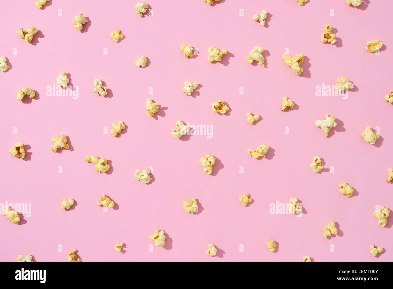 Food pattern from delicious popcorn on a light pink background. Stock Photo