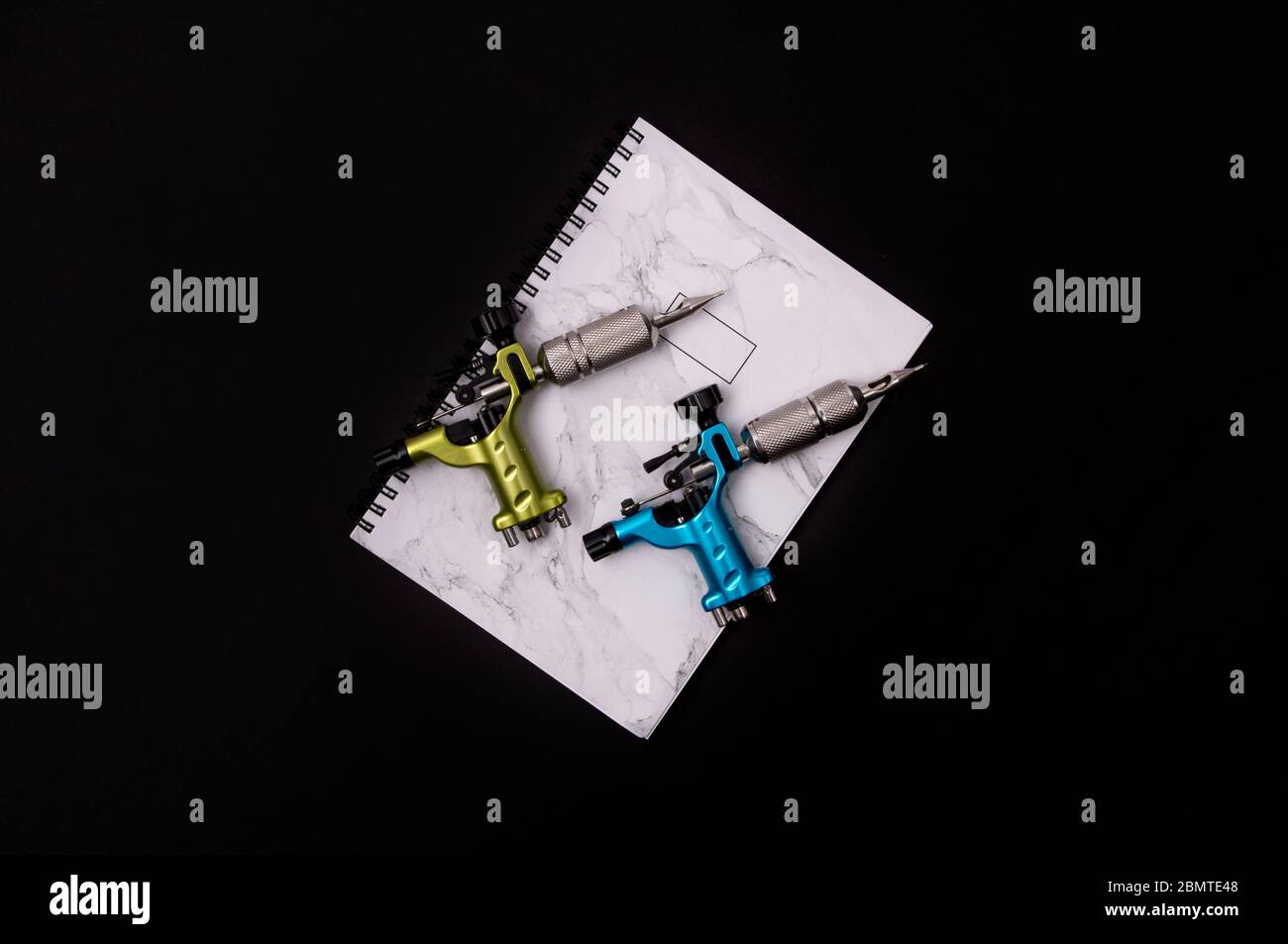Tattoo machines with notepad on black background. Tattooing artist