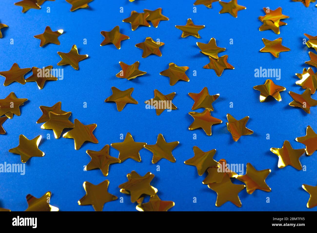 Gold confetti made from stars on blue. Bright festive pattern Stock Photo