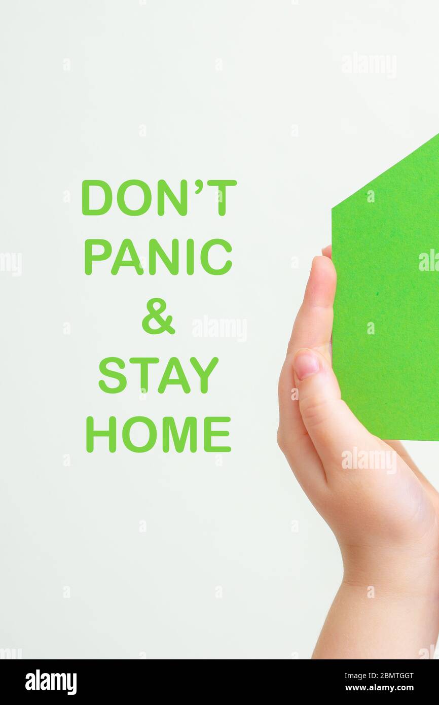 Children's hands holding a green paper house with words Stay Home on white background. Stay home concept. Stock Photo