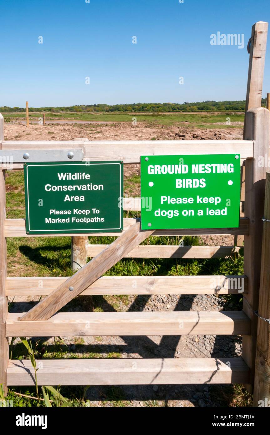 Wildlife Conservation Area and Ground Nesting Birds signs attached to a gate on a footpath crossing Norfolk marshes. Stock Photo